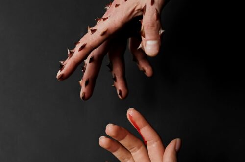 Thorned hand reaching for innocent hand that is bleeding