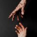 Thorned hand reaching for innocent hand that is bleeding